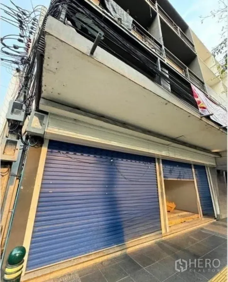 อาคารพาณิชย์ ให้เช่าในPhaya Thai, Bangkok - มุมมองด้านหน้าแสดงประตูม้วนสีน้ำเงินกว้างระดับทางเท้า