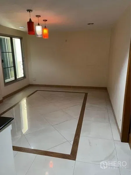 Townhouse for sale in Phra Khanong, Bangkok - Bright dining area with white tile inlay, colorful pendant lights, and a sliding window.
