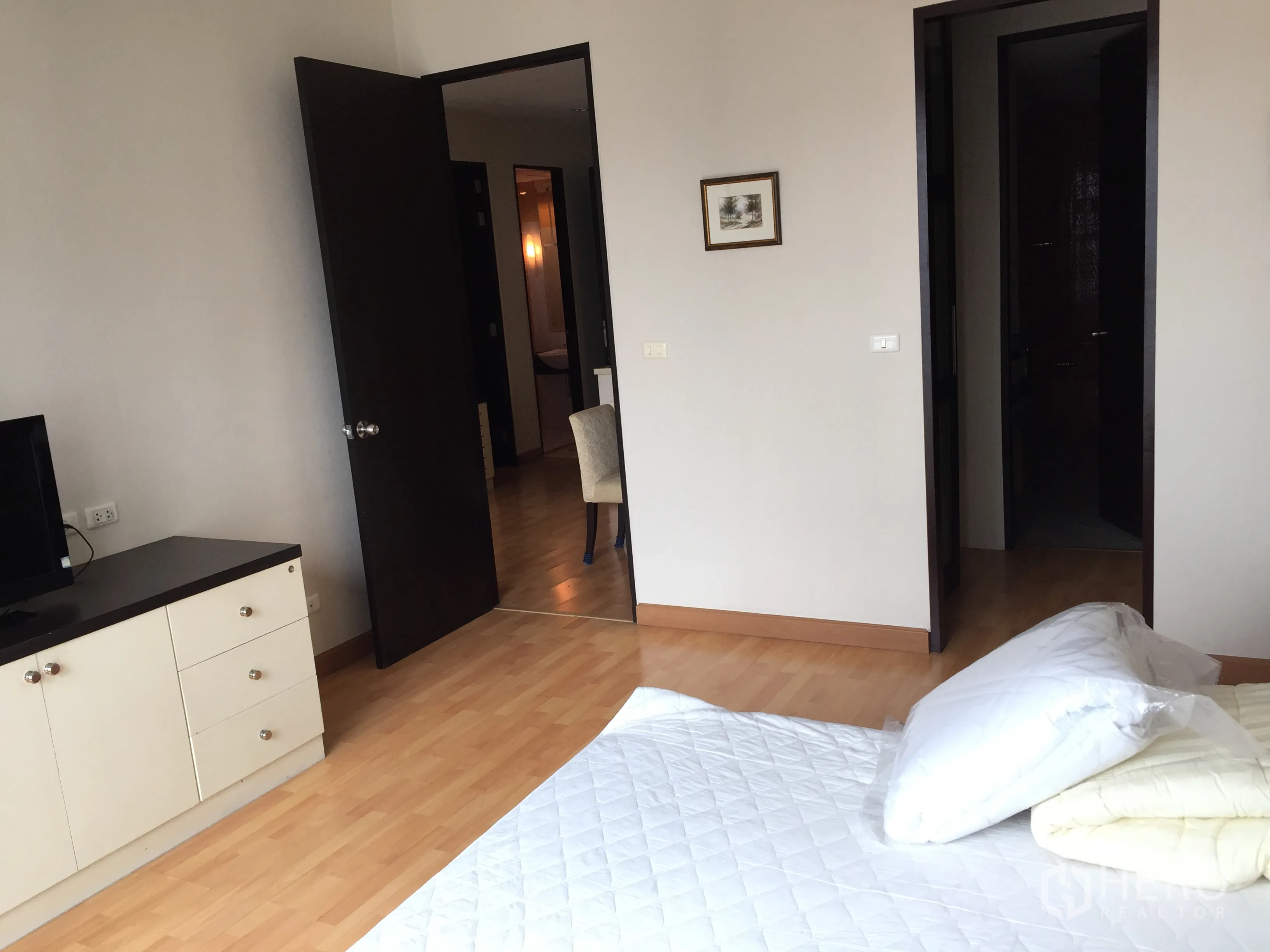 Condominium for rent in Khlong Toei, Bangkok - Spacious bedroom with storage cabinet and doors to ensuite and hallway.
