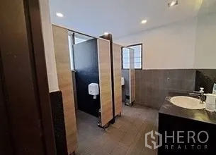 Retail Space for rent in Bangkok - Restroom with partitioned stalls, tiled walls and a countertop sink.