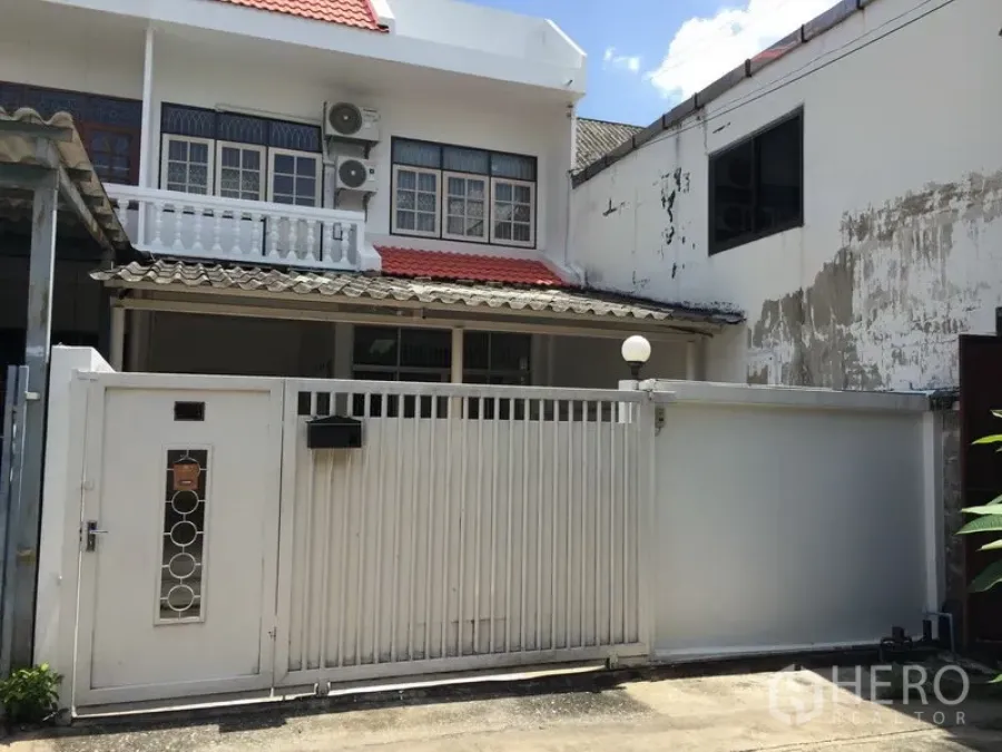 Townhouse for rent in Phra Khanong, Bangkok - Two-storey townhouse facade with white gate, balcony and red roof tiles.