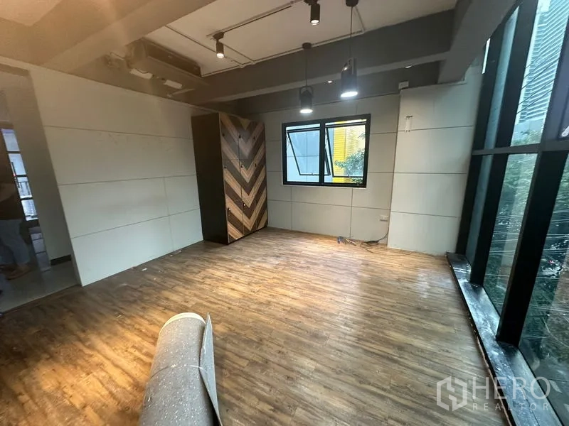 Office Space for rent in Bang Rak, Bangkok - Smaller office section with pendant lights, wood-look floor, window, and glass façade along one side.