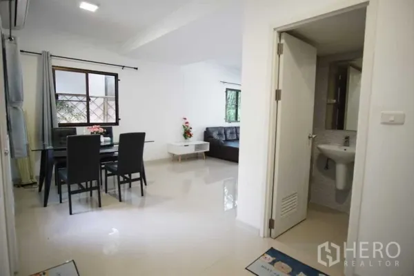 Townhouse for rent in Suan Luang, Bangkok - Open-plan dining and living area with a guest bathroom and glossy tile floors.