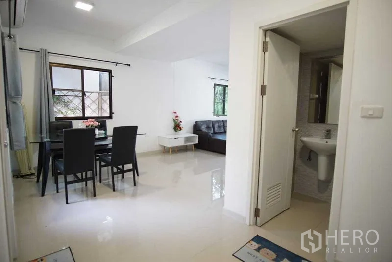 Townhouse for rent in Suan Luang, Bangkok - Open-plan dining and living area with a guest bathroom and glossy tile floors.