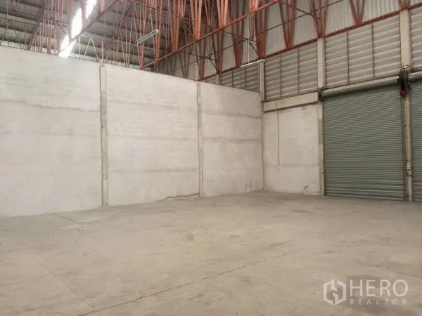 Warehouse for rent in Min Buri, Bangkok - Wide loading zone facing a roller shutter door with ventilated upper panels.