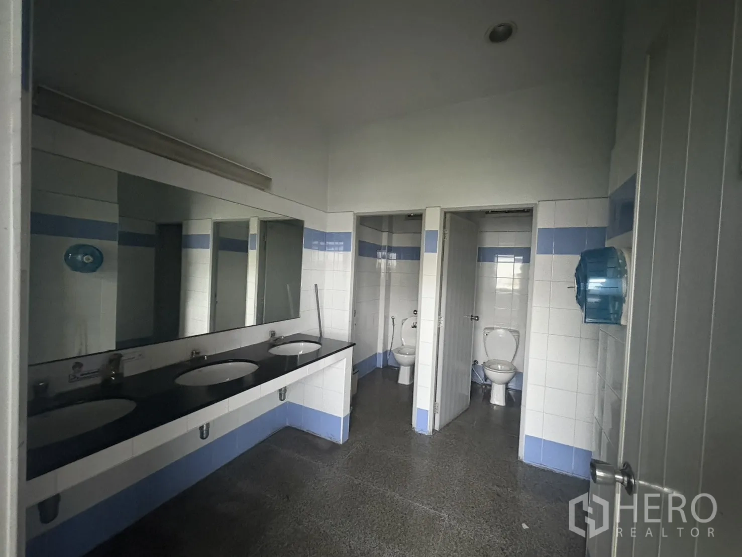 Factory for rent in Khlong Toei, Bangkok - Clean tiled restrooms with multiple cubicles and a long sink counter.
