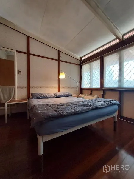 Detached House for rent in Mueang Samut Prakan, Samut Prakan - Bright bedroom with a double bed, corner windows and polished wood flooring.