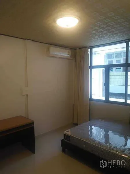 Townhouse for rent - Air-conditioned bedroom with large window, curtains, and a bed frame.