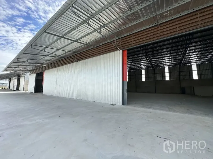 Warehouse for rent in Lam Luk Ka, Pathum Thani - Row of modern warehouses showing open bays, metal cladding and a sheltered truck loading area.