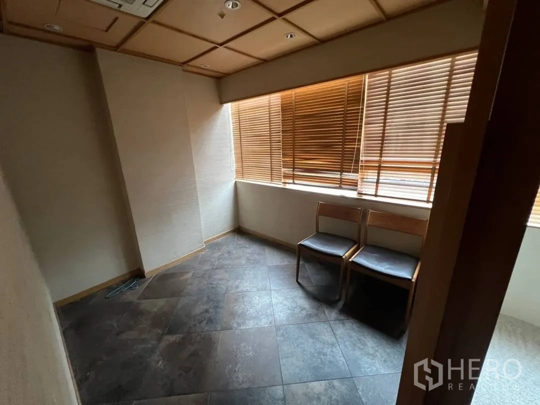 Retail Space for rent - Compact room with stone-look tiles, corner windows and wooden blinds.