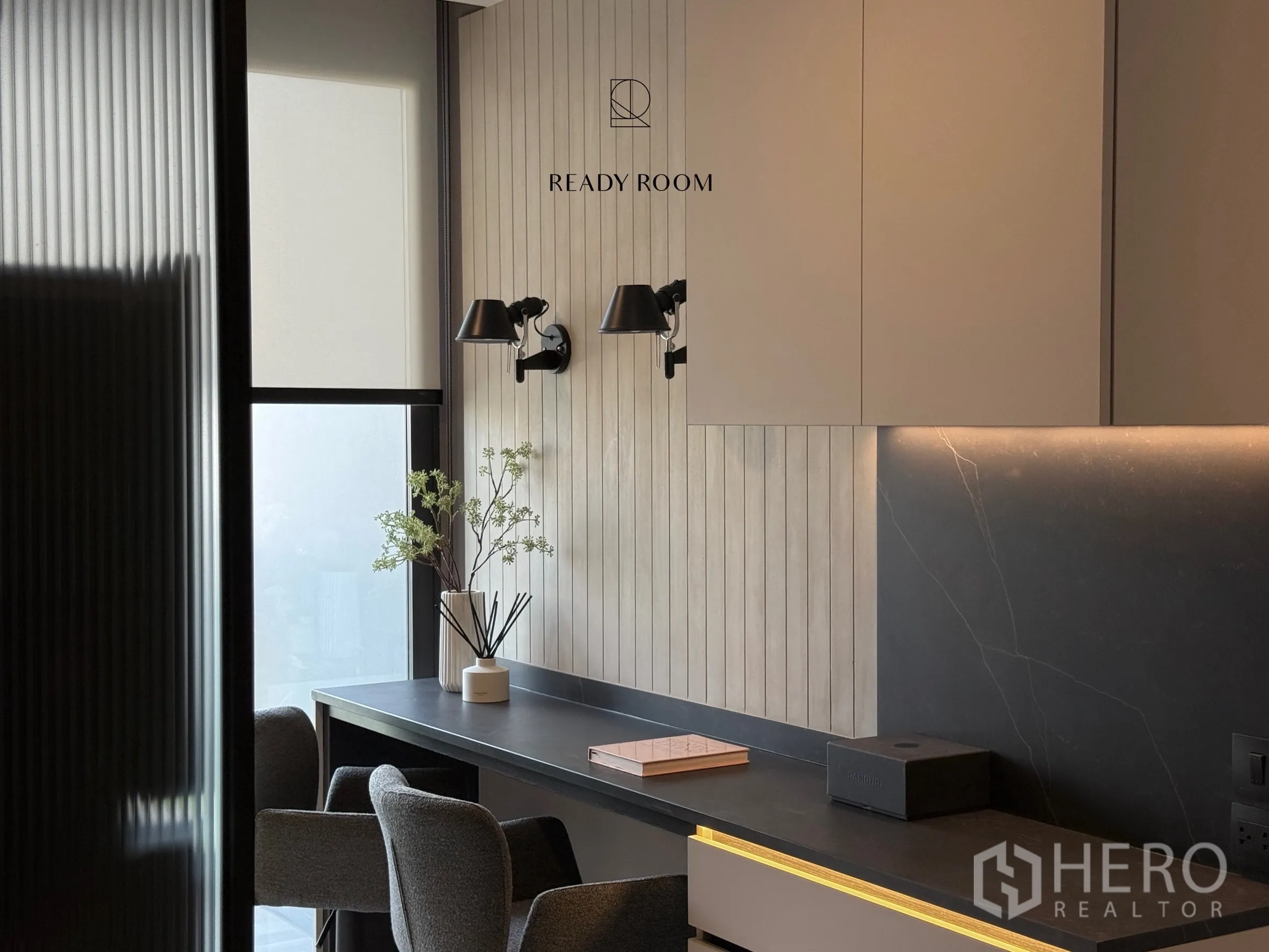 Condominium for rent in Khlong Toei, Bangkok - Long built-in desk with wall sconces by a window and overhead cabinets.