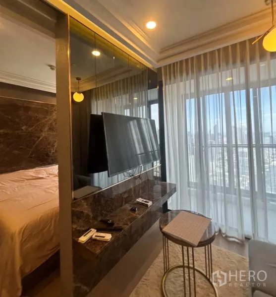 Condominium for rent in Bang Rak, Bangkok - TV on a marble console facing the bed, with sheer curtains and large windows to the balcony.