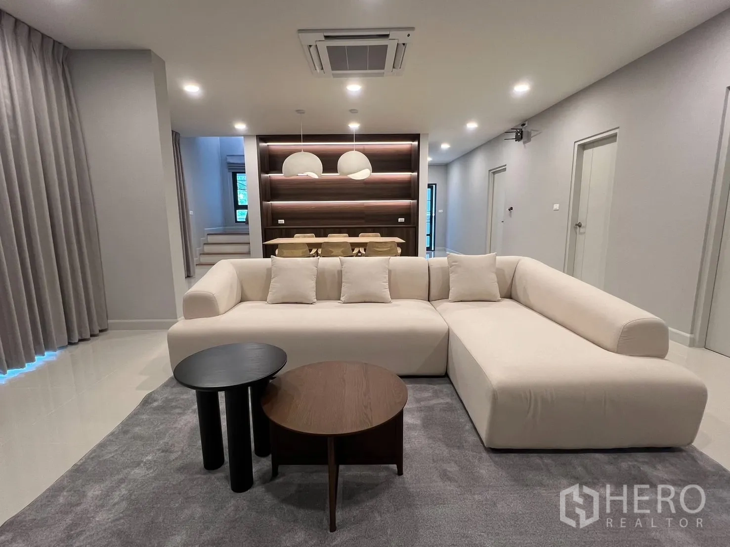 Detached House for rent in Bang Phli, Samut Prakan - Spacious living room with an L-shaped cream sofa, nesting coffee tables and recessed lighting.