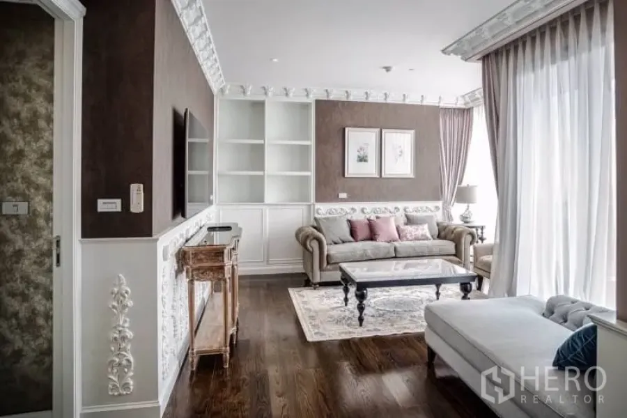 Condominium for rent or sale in Khlong Toei, Bangkok - Bright living room with classic mouldings, built-in shelves, sofa set and floor-to-ceiling curtains.