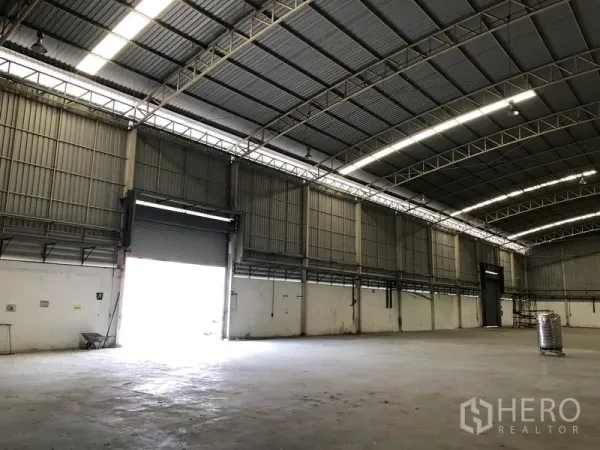 Factory for rent in Phra Nakhon Si Ayutthaya - Warehouse interior showing a large roller shutter loading bay and long‑span roof suitable for trucks.