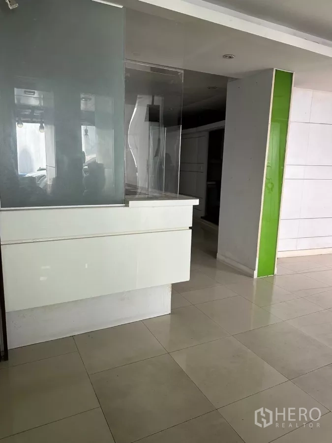 Shophouse for sale in Watthana, Bangkok - Ground-floor reception counter with glass partitions and glossy tiled floor.