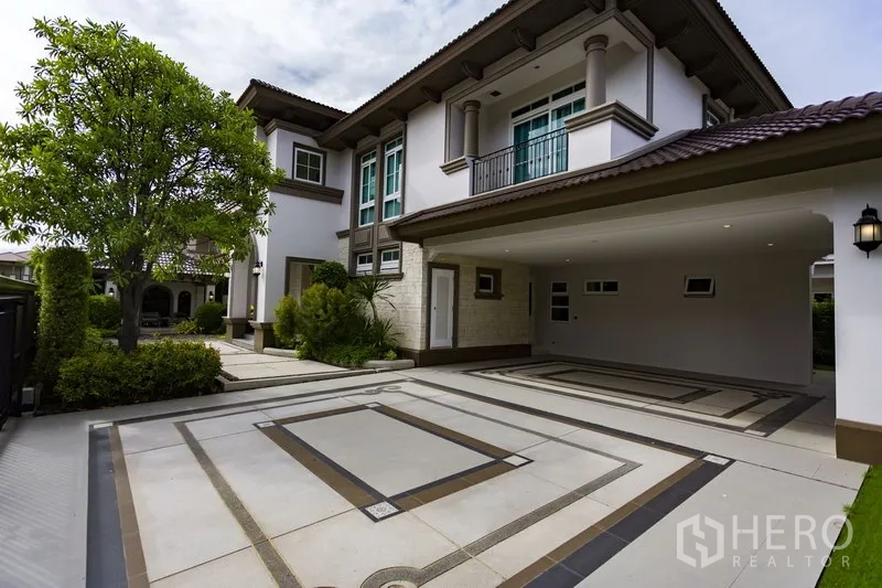 Detached House for rent in Mueang Samut Prakan, Samut Prakan - Spacious driveway and covered carport beside a landscaped garden at a modern two-storey home.
