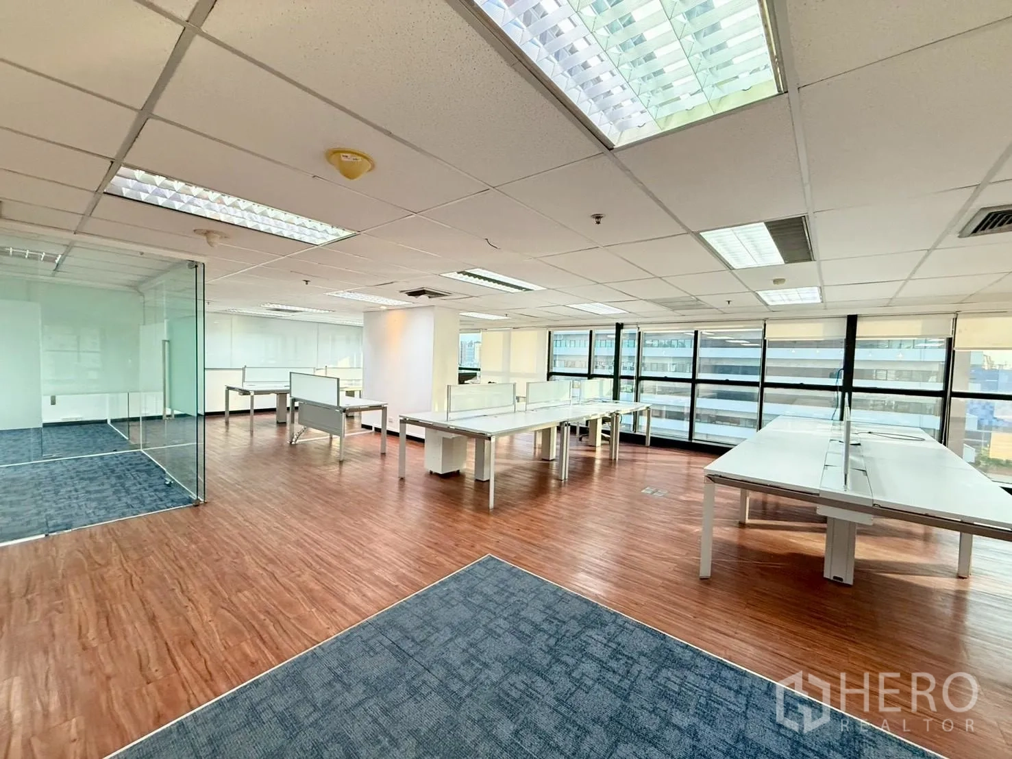 Office Space for rent in Watthana, Bangkok - Open-plan office with expansive windows, roller blinds, and white bench desks.