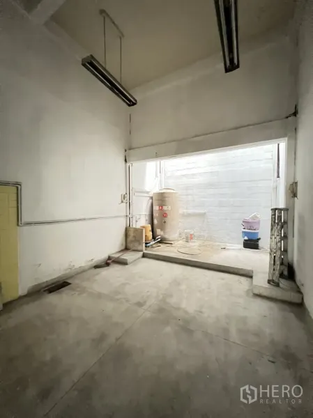 Shophouse for rent in Phra Khanong, Bangkok - Rear utility zone with high ceiling, fluorescent lights and lightwell, including water tank and storage area.