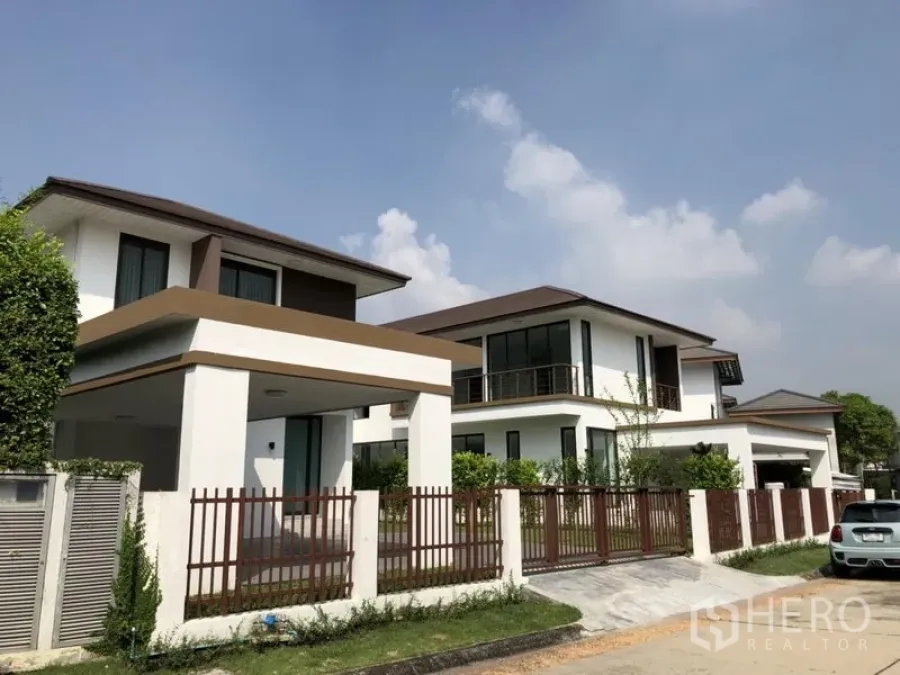 Detached House for rent in Prawet, Bangkok - Modern two-storey detached houses with fenced yards and covered carports on a quiet street.