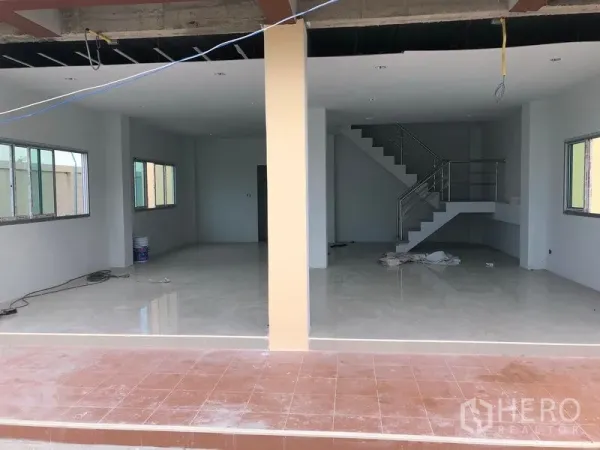 Factory for rent or sale in Khlong Luang, Pathum Thani - Open-plan ground-floor office or showroom with a metal staircase, shown mid-renovation.