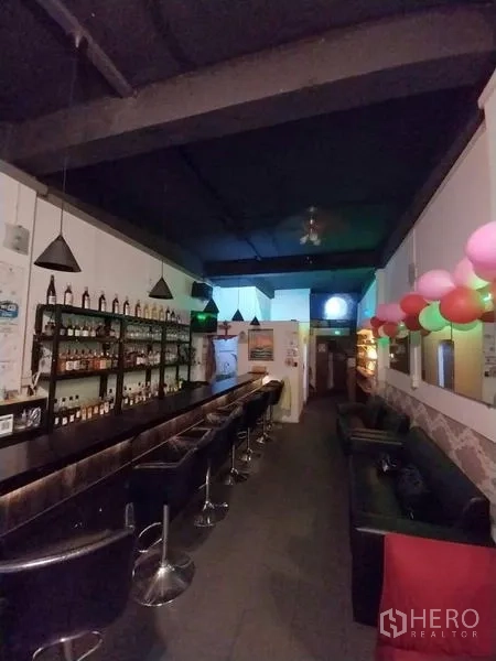 Shophouse for rent in Khlong Toei, Bangkok - Interior with bottle racks, long counter and sofa seating under dark ceiling lights.