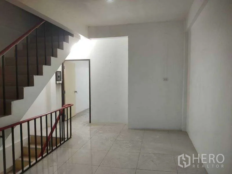 Shophouse for sale in Phra Khanong, Bangkok - Stairwell area with tiled floor and white walls inside the shophouse.