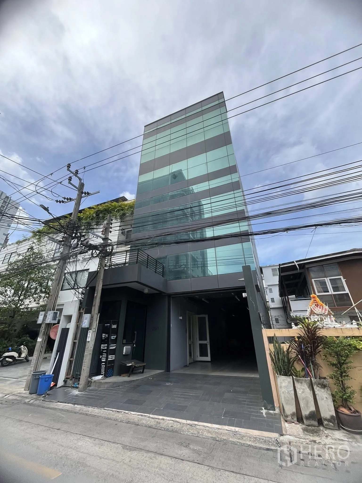 Home Office for rent in Watthana, Bangkok - Modern glass-façade building exterior with a covered entrance.