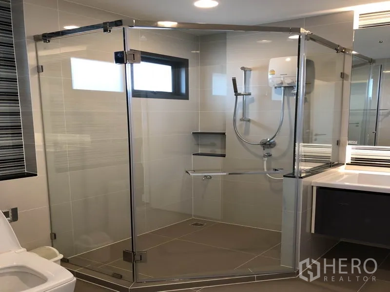 Detached House for rent or sale in Bang Kapi, Bangkok - Contemporary bathroom with frameless glass shower enclosure and wall-mounted water heater.