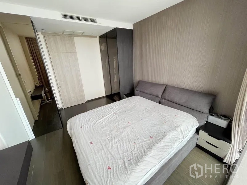 Condominium for rent in Pathum Wan, Bangkok - Master bedroom with upholstered bed, built-in wardrobes, and wood flooring.