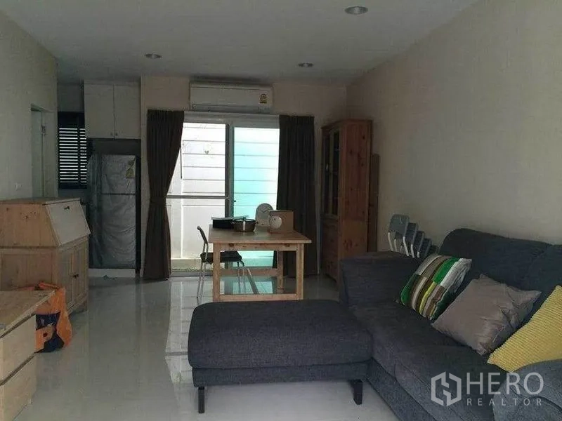 Townhouse for sale in Suan Luang, Bangkok - Open-plan living and dining area in Suan Luang townhouse with sofa, table and sliding glass door.