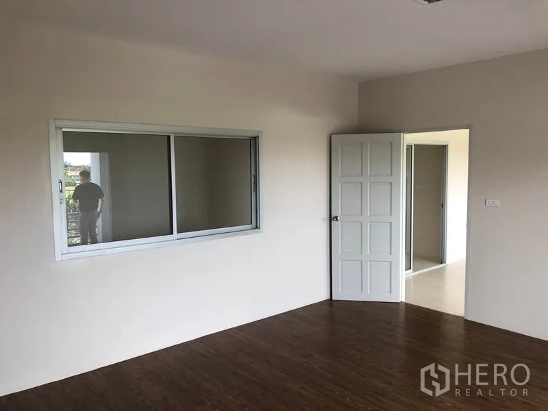 Factory for rent in Pak Kret, Nonthaburi - Upstairs office room with window, wood-style flooring and white door.