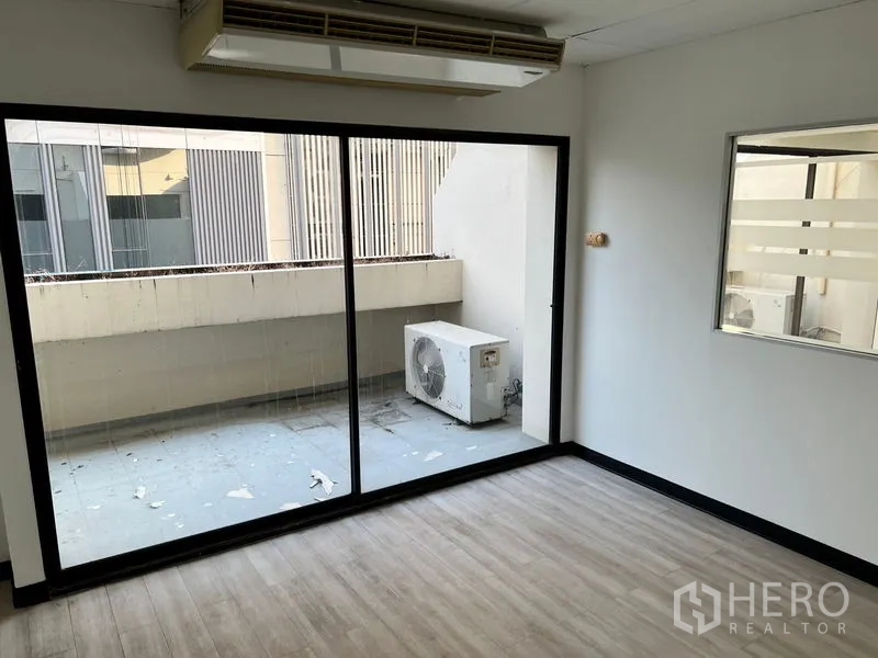 Office Space for rent in Pathum Wan, Bangkok - Private room with large sliding glass door to a balcony and wall-mounted air conditioner.