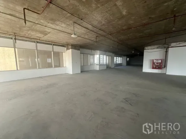 办公空间 出租在Watthana, Bangkok - 大面积开放式办公楼层，裸露混凝土顶，周边窗户与墙面消防栓。