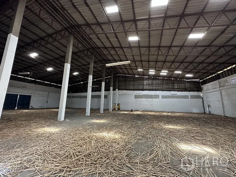 Warehouse for rent in Samut Prakan - Spacious warehouse interior showing high steel-truss ceiling, skylights, and multiple support columns over an open floor.