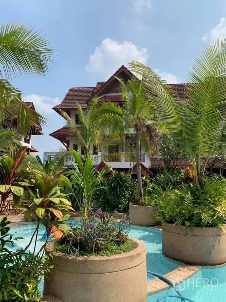 Townhouse for rent in Watthana, Bangkok - Townhouse exterior amid tropical landscaping and a decorative water feature.