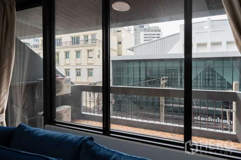 Apartment for rent in Khlong Toei, Bangkok - View from the living room window to the balcony and neighboring buildings.