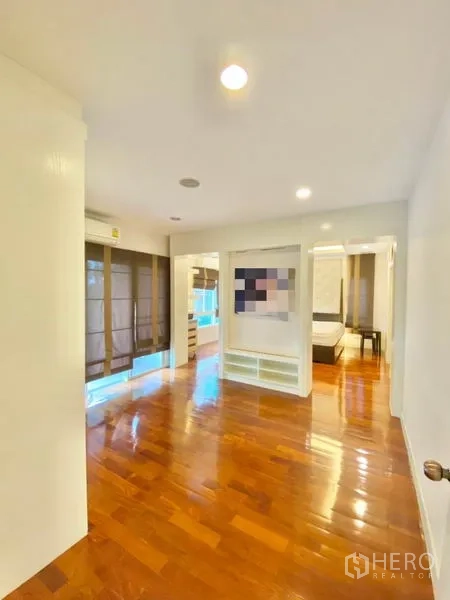Detached House for sale in Khan Na Yao, Bangkok - Spacious bedroom with polished wooden flooring, large windows with blinds, and access to an ensuite bathroom.