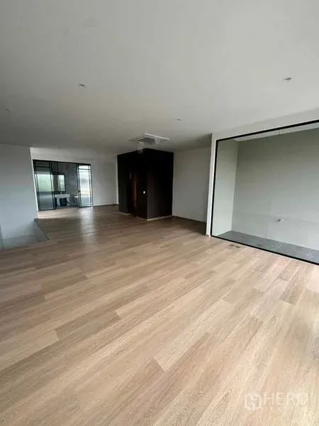 Home Office for rent or sale in Lat Phrao, Bangkok - Open-plan office room with warm wood flooring and a glass-walled area for meetings.