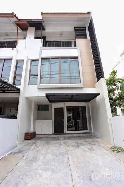 Townhouse for rent in Phra Khanong, Bangkok - Modern three-storey townhouse facade with wide windows and a covered carport.