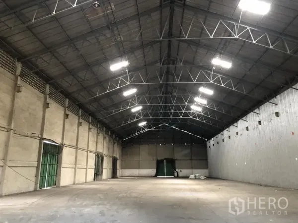 Warehouse for rent in Mueang Pathum Thani, Pathum Thani - Spacious warehouse interior with high steel truss roof, bright lighting and multiple access doors.