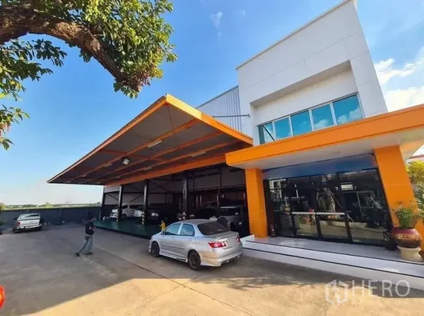Warehouse for rent in Thanyaburi, Pathum Thani - Modern warehouse exterior with orange canopy, glass-fronted office and ample driveway parking.