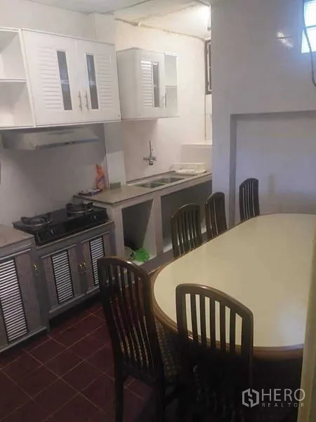 Townhouse for rent - Functional kitchen with gas hob, white cabinets, and a dining table with chairs.