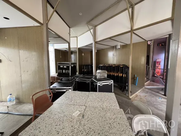 Retail Space for rent in Khlong Toei, Bangkok - Open retail space with structural columns, storage flight cases, stacked barriers and terrazzo-top tables.
