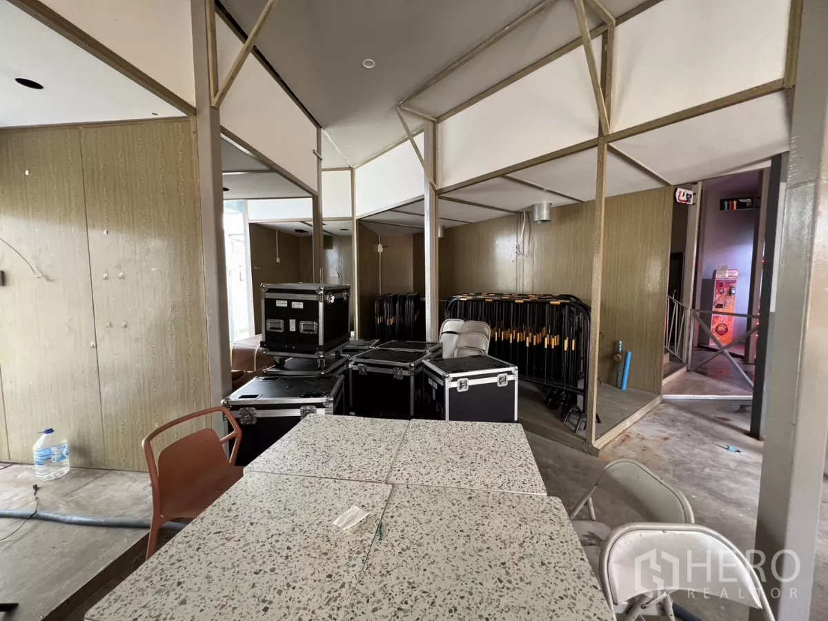 Retail Space for rent in Khlong Toei, Bangkok - Open retail space with structural columns, storage flight cases, stacked barriers and terrazzo-top tables.