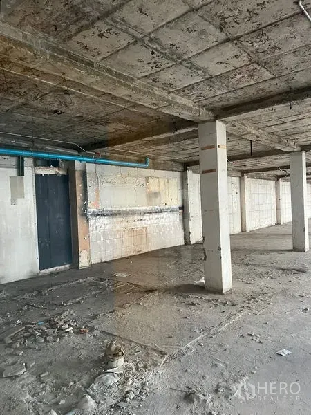 Retail Space for rent in Watthana, Bangkok - Raw retail unit interior showing concrete columns, unfinished walls, and visible utility piping.