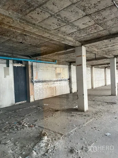 Retail Space for rent in Watthana, Bangkok - Raw retail unit interior showing concrete columns, unfinished walls, and visible utility piping.
