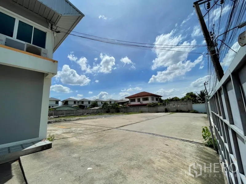 Warehouse for rent in Bang Kapi, Bangkok - Expansive concrete yard inside a fenced compound beside the warehouse, suitable for parking and loading.