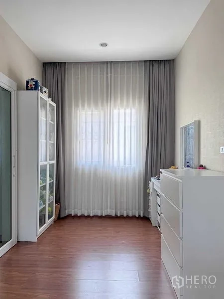 Detached House for rent or sale in Bang Khen, Bangkok - Compact multipurpose room featuring tall display cabinet, dresser and sheer curtains.