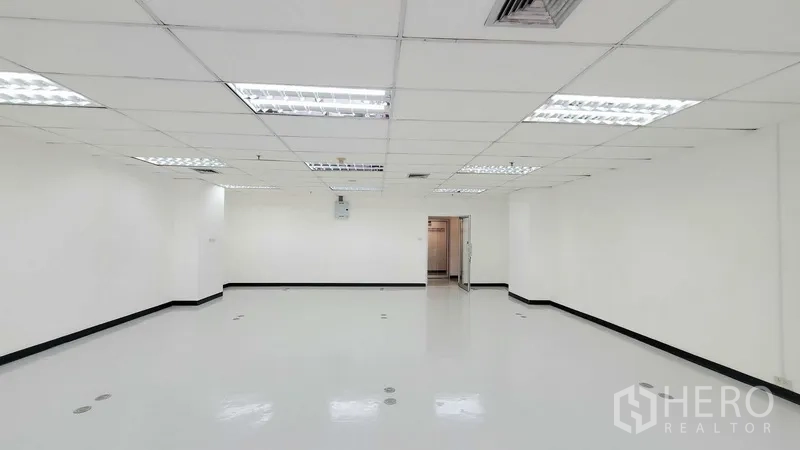 Office Space for rent in Watthana, Bangkok - Spacious empty office with white walls, ceiling lights, floor outlet points, and a glass entry door.
